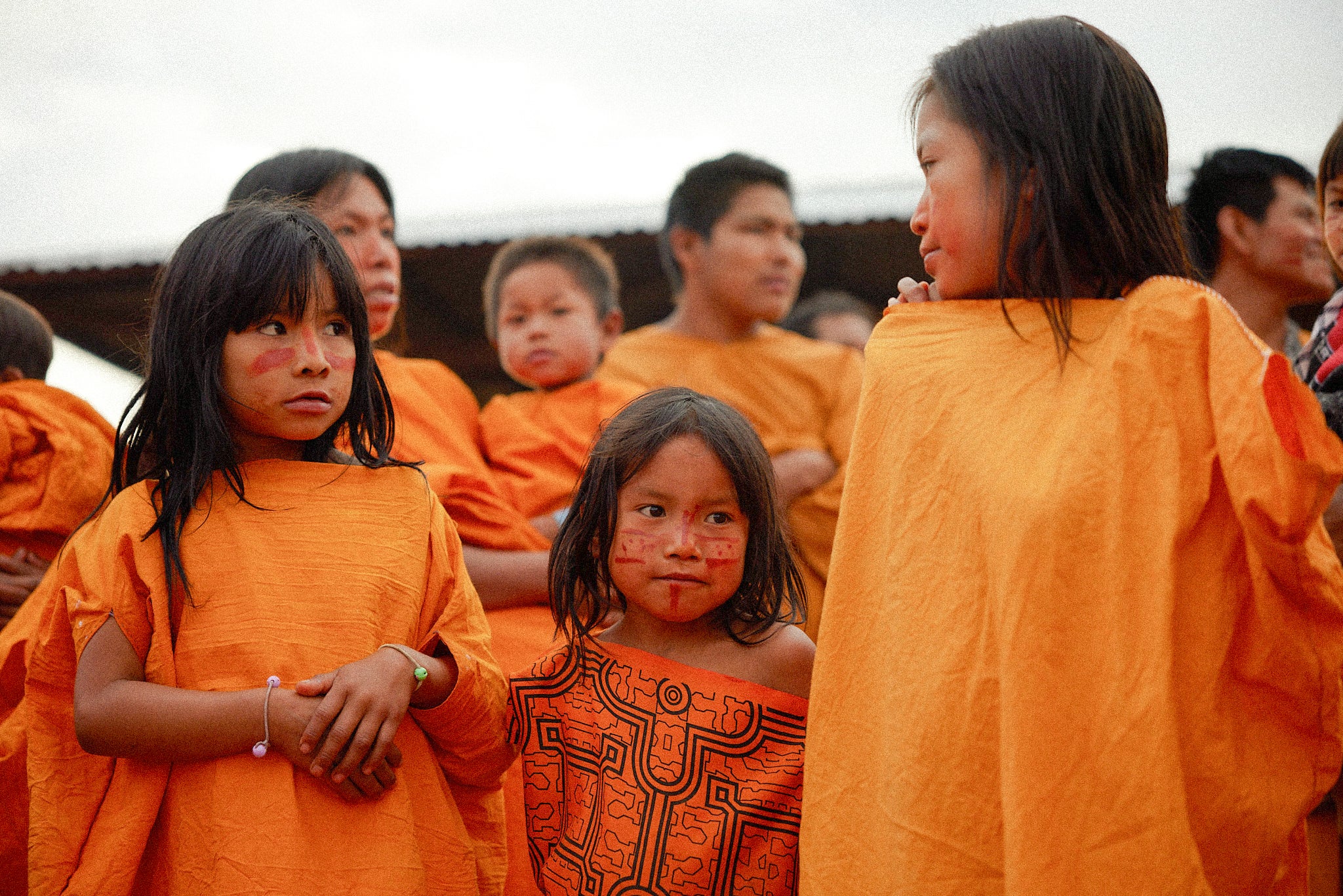 Indigenous children in orange robes standing together outdoors